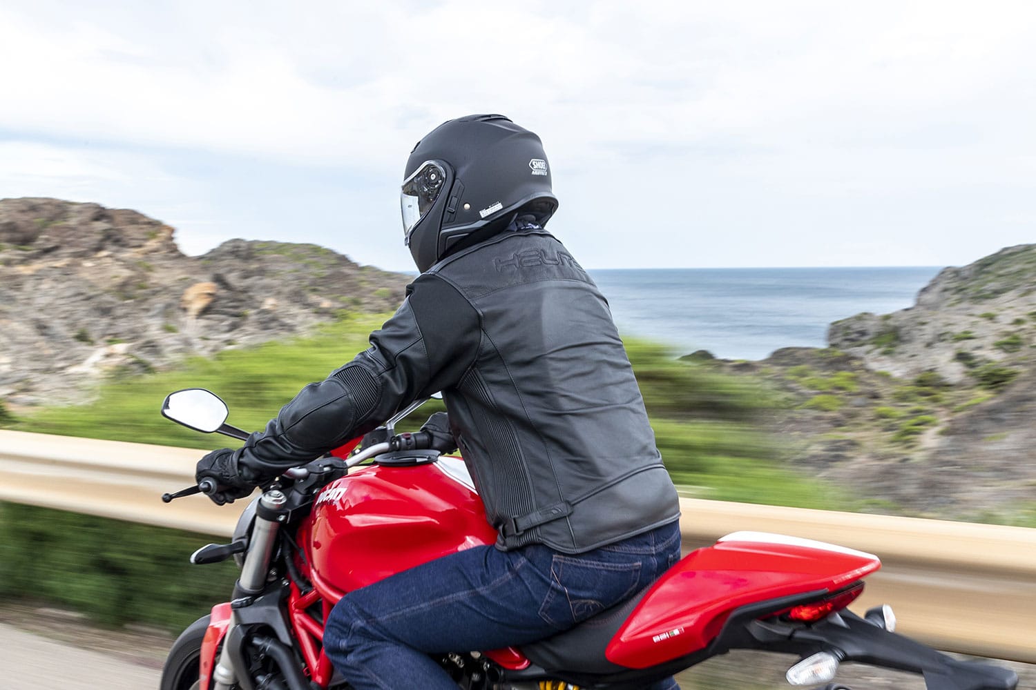 Man riding motorbike wearing roadster leather jacket rear view